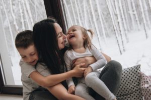woman-with-two-kids-playing-inside-snow-outside-windows